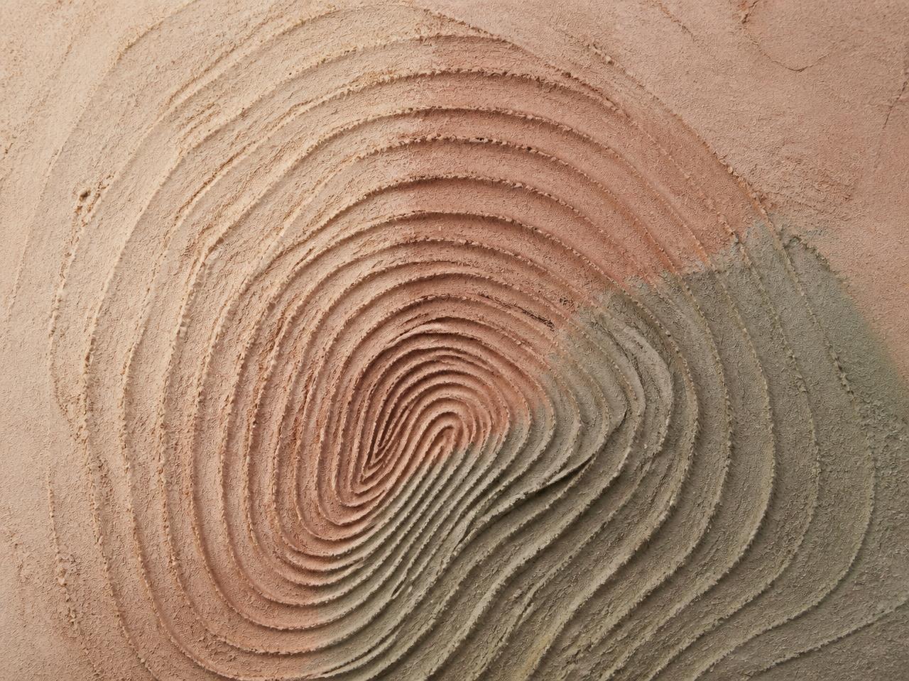 Close-up of fingerprint-like contour lines pressed into sand and clay